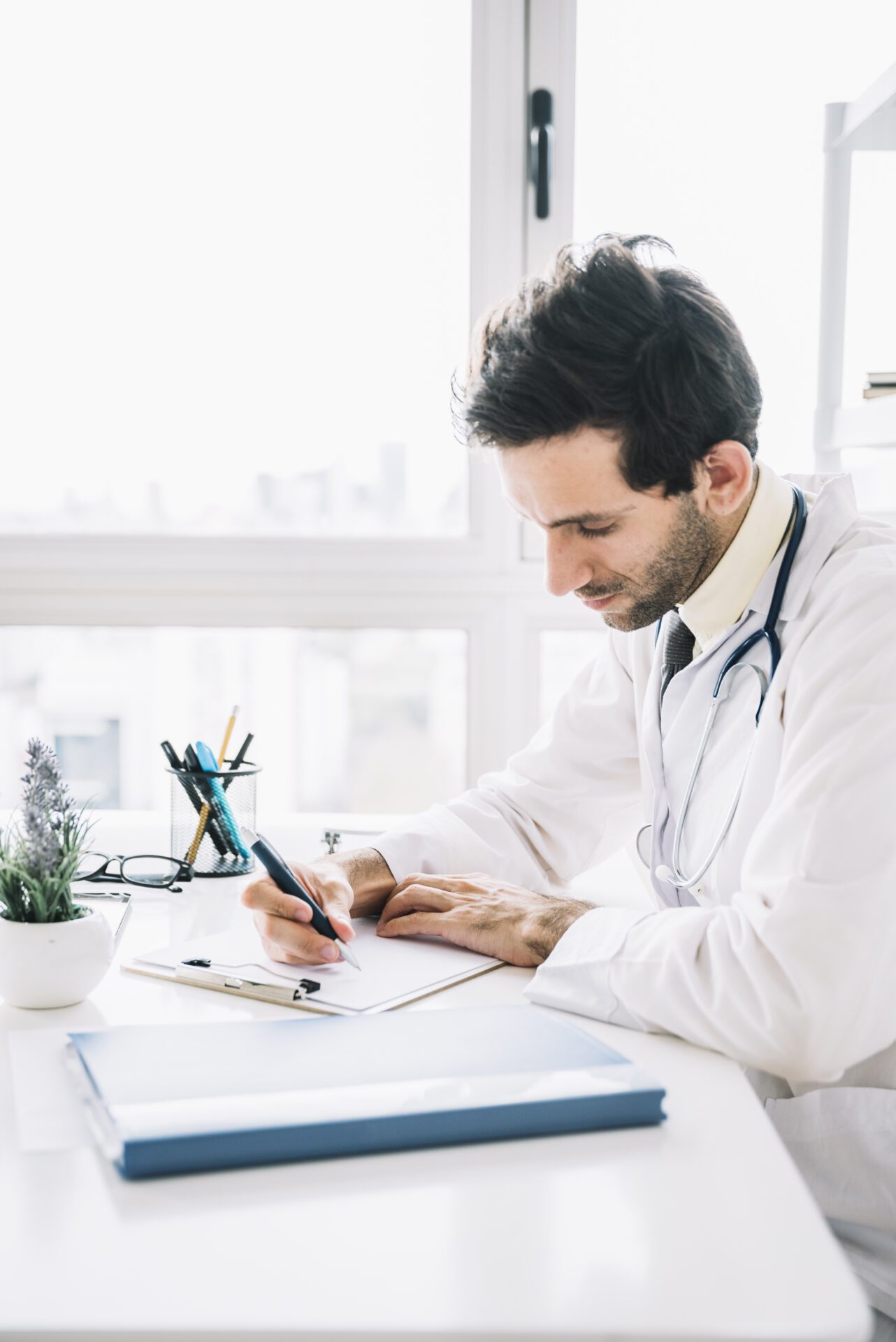 young-male-doctor-writing-clipboard-clinic